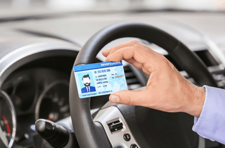 A man showing his driver's license inside his car